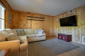 Ein Zimmer mit Holzvertäfelung, einer Couch, einem Flachbildfernseher und einer dekorativen Schachtel.