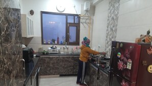 Una cucina con un piano di lavoro in marmo, un frigorifero con calamite e una finestra sopra il lavello.