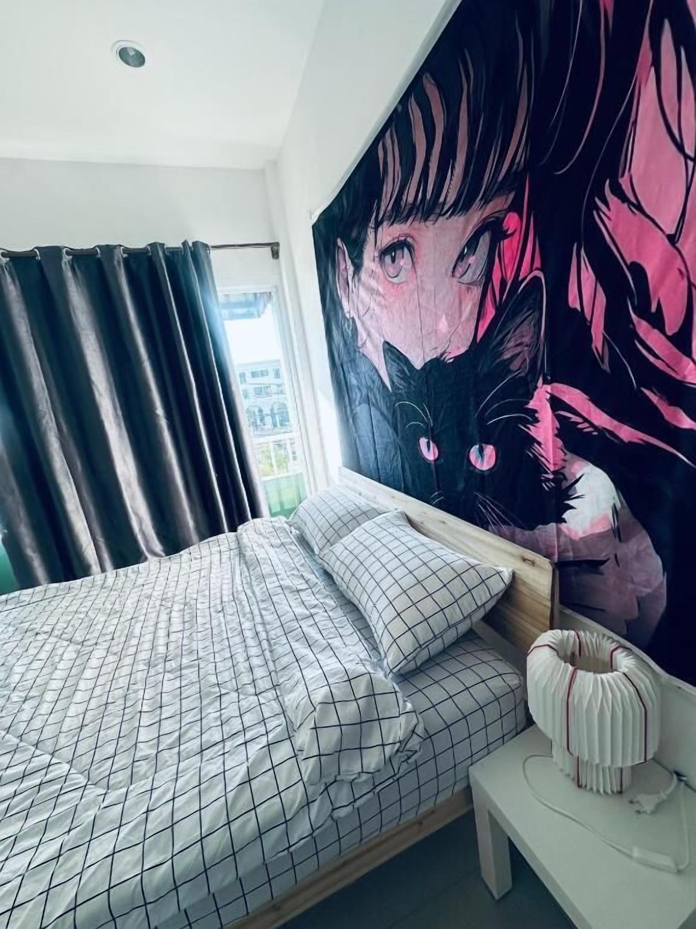 A bedroom with a bed, a large wall mural, a window with curtains, and a bedside table.