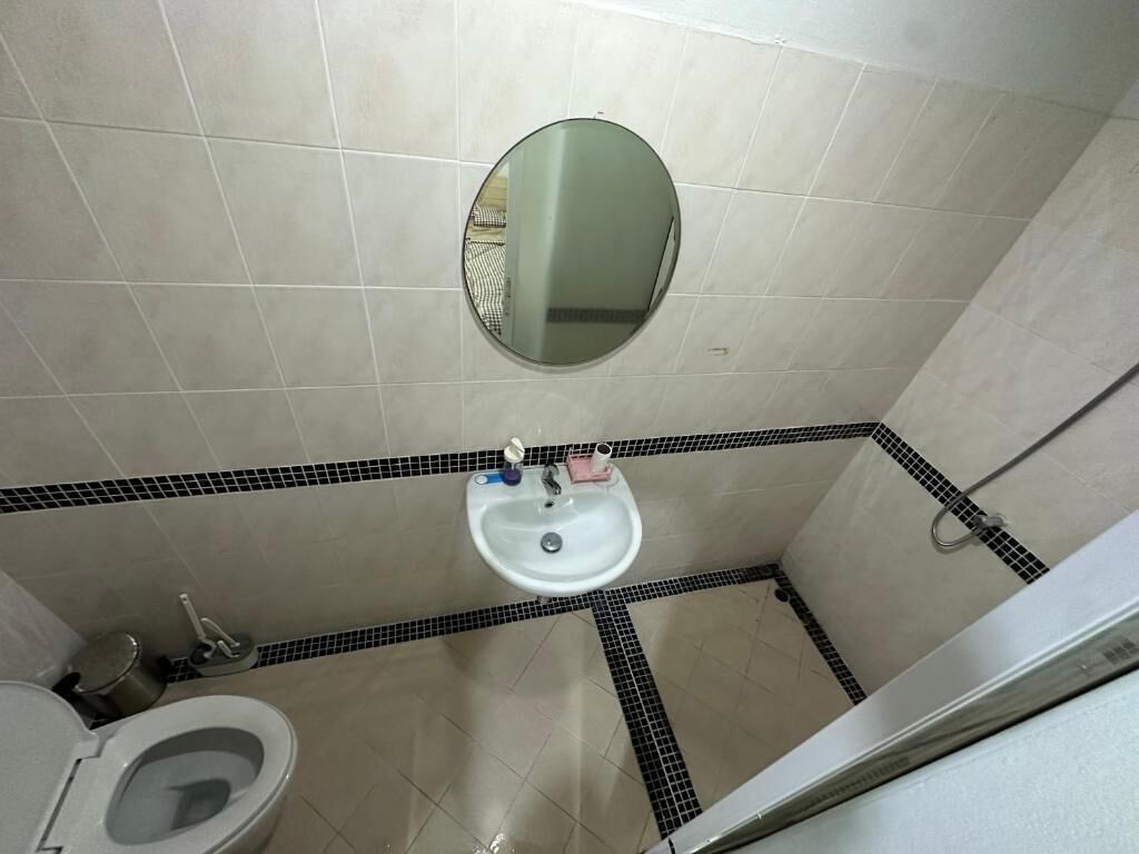 A bathroom with a toilet, sink, and mirror.