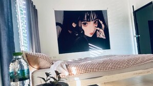 A room with a bed, a potted plant, a water bottle, and a poster on the wall. - HulaFling Homestay  (Sa Khu)