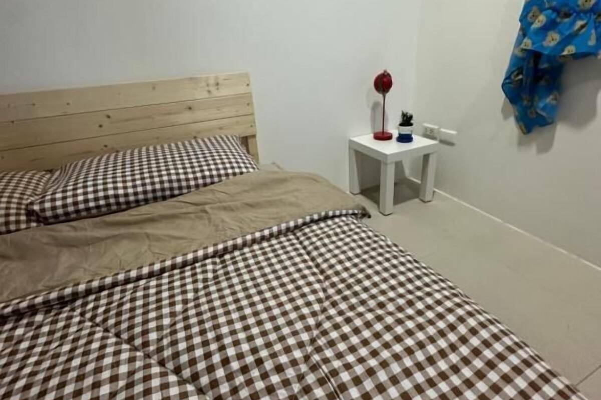 A bedroom with two beds, a nightstand, a lamp, and a blue curtain.