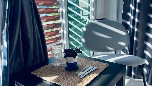 A modern dining area with a table, a chair, a potted plant, and a glass of water. - HulaFling Homestay  (Sa Khu)
