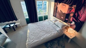 A bedroom with a bed, a desk, a chair, a window with curtains, and a large poster on the wall. - HulaFling Homestay  (Sa Khu)