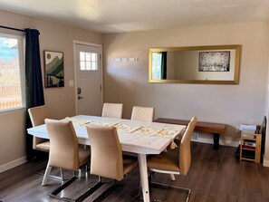 Ein Essbereich mit Tisch, Stühlen, einer Bank und einem Spiegel an der Wand.