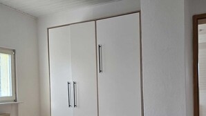 Un dormitorio con un armario grande, una cama y una ventana.