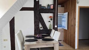 Un comedor con una mesa de madera, sillas y un techo con vigas a la vista.