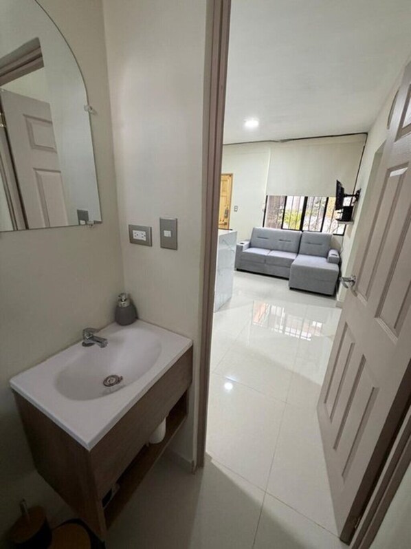 Une salle de bain avec un lavabo, un miroir et des toilettes.