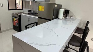 Een moderne keuken met een marmeren eiland, roestvrijstalen apparatuur en een raam met zonwering.