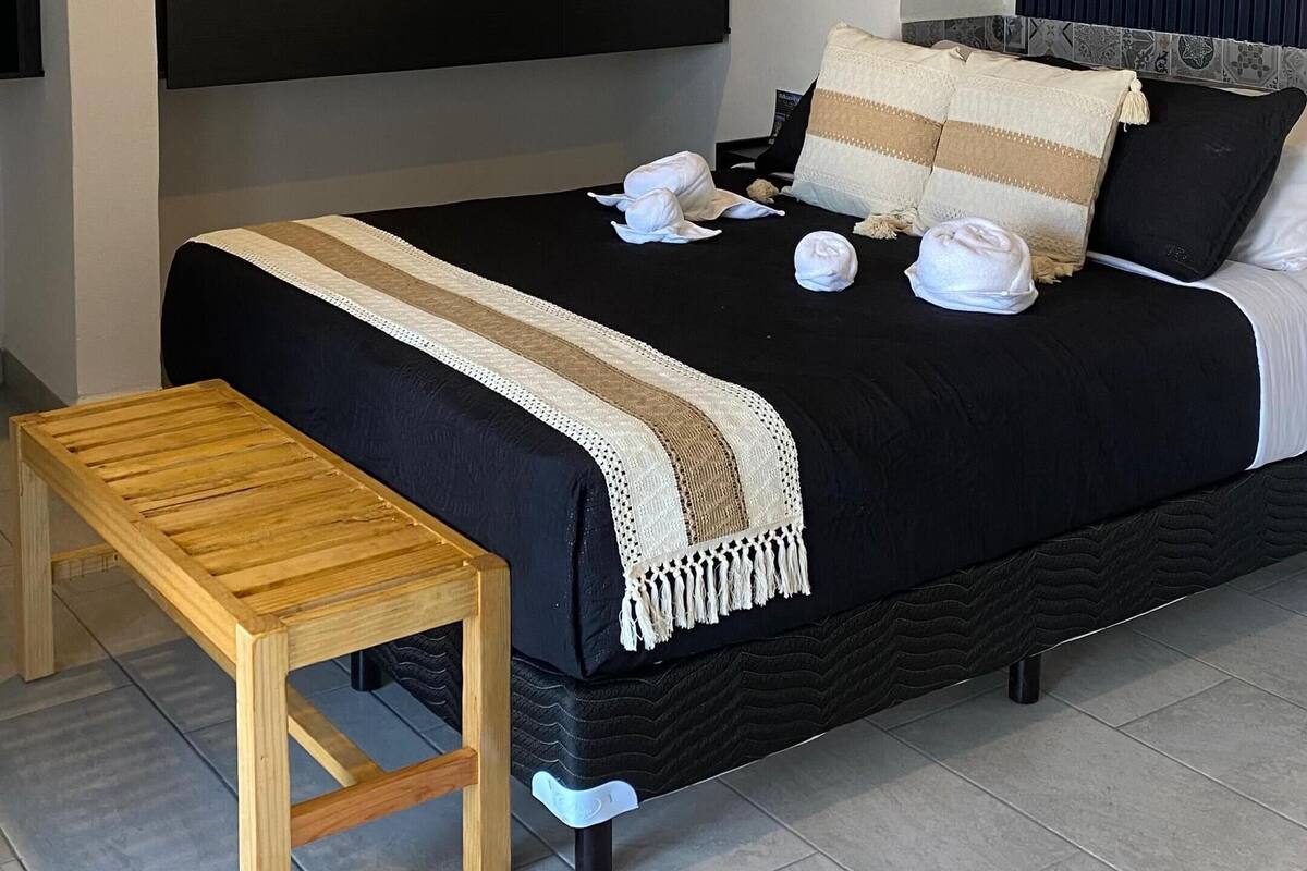 A modern bedroom with a bed, bedside table, ceiling fan, and built-in shelving.