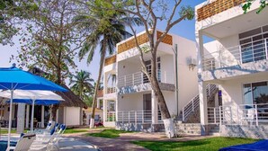 A resort with a swimming pool, lounge chairs, and a covered seating area. - Pelicanos  (Alvarado)