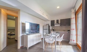 A modern kitchen with a dining area, a TV, and a refrigerator. - Sute StyleHouse Apartment (Olbia)