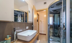 A modern bathroom with a large mirror, a built-in sink, and a glass-enclosed shower. - Center Style House Apartment (Olbia)