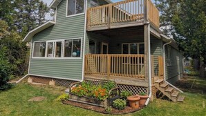 A two-story house with a wooden deck and a small garden. - Steps from the Shore, Modern Beachy Getaway (Dunnottar)