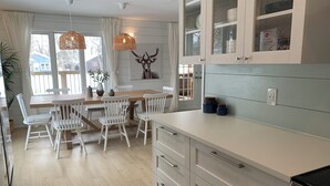 A modern kitchen with white cabinetry, a wooden dining table, and a built-in oven. - Steps from the Shore, Modern Beachy Getaway (Dunnottar)