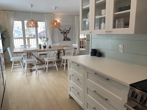 A modern kitchen with white cabinetry, a wooden dining table, and a built-in oven.