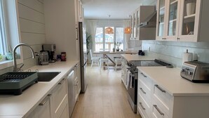 A modern kitchen with white cabinetry, a built-in oven, a sink, and a toaster. - Steps from the Shore, Modern Beachy Getaway (Dunnottar)