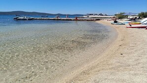 A beach with clear shallow water, a jetty, and beach chairs. - Mobile Home Paradise (Sveti Filip i Jakov)