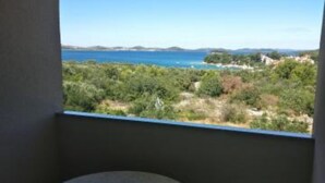 Ein Balkon mit Blick auf eine Küstenlandschaft, einschließlich Grünflächen und eines Gewässers.