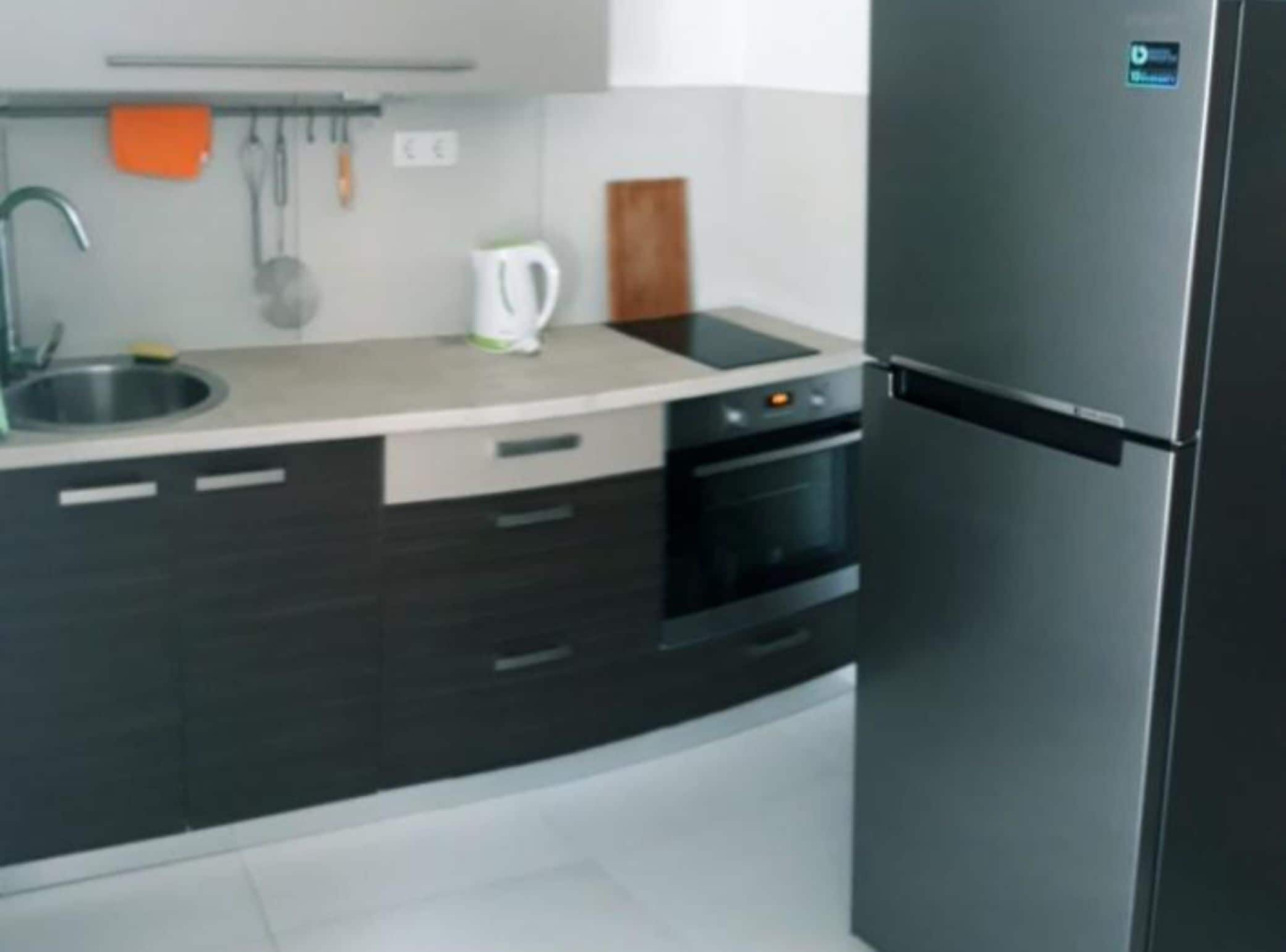 A modern kitchen with a built-in oven, a refrigerator, and a sink.