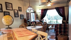 A dining area with a wooden table, chairs, a globe, and a ceiling fan. - Charming 2-bedroom farmhouse in Willamina's relaxing countryside. (Willamina)