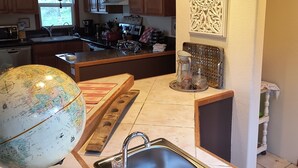 A kitchen with wooden cabinets, a globe, a sink, and a decorative wall piece. - Charming 2-bedroom farmhouse in Willamina's relaxing countryside. (Willamina)