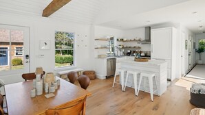 Eine moderne Küche mit weißen Schränken, einem Holzespeisetisch und einem großen Fenster.