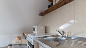 Una cocina moderna con un lavamanos de acero inoxidable, un microondas y armarios de madera.