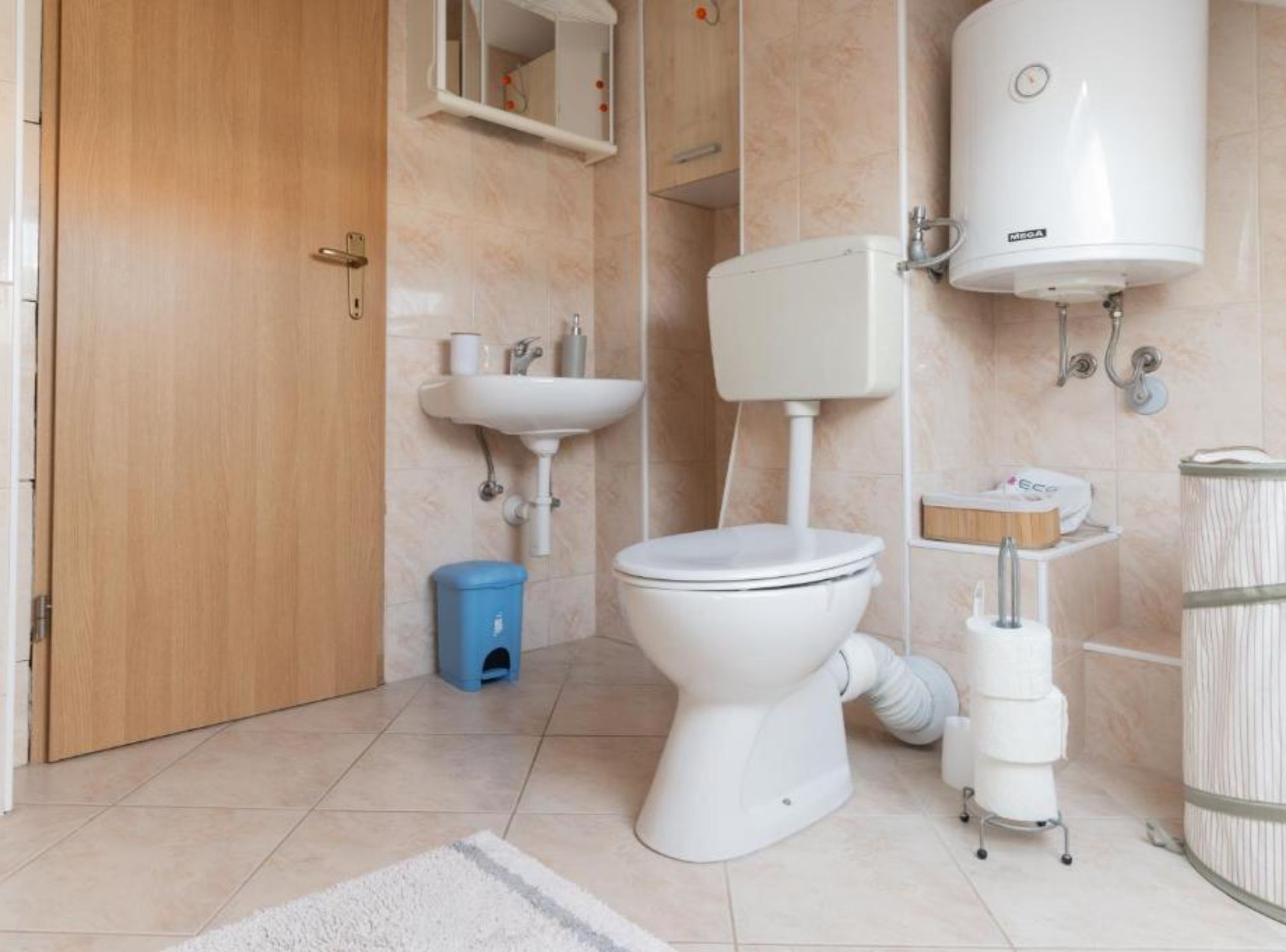 Een badkamer met toilet, wastafel en een boiler.