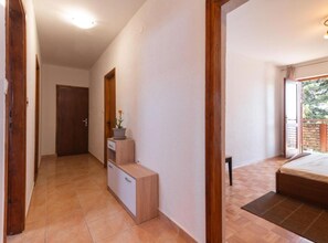 Une chambre à coucher avec un lit, une petite table de chevet, une plante en pot et une vue sur l’extérieur.