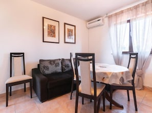 Un'area pranzo con tavolo, sedie, un divano e due quadri appesi al muro.