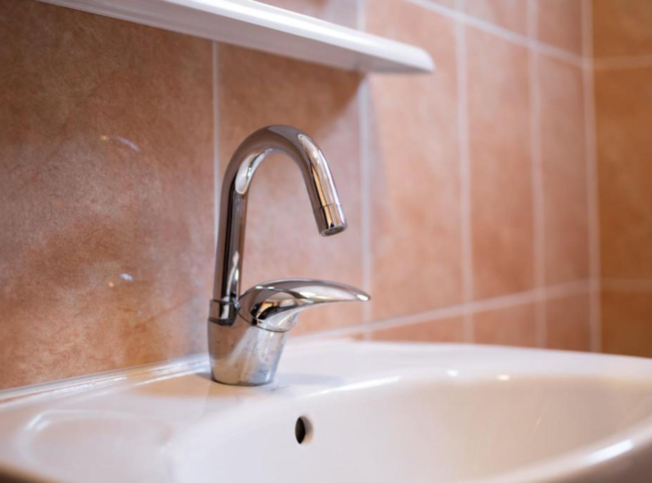 A bathroom sink with a chrome faucet and a white countertop.