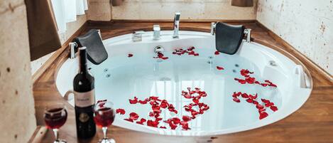 Ein Zimmer mit Badewanne, einer Holzbank, Vorhängen und einem Fenster.