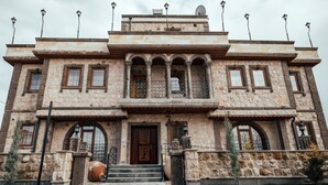 A historic stone building with a central entrance, arched windows, and a balcony with railings. - Kallista Cappadocia (Nevsehir)