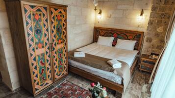 A bedroom with a bed, a wardrobe, a nightstand, and a wall-mounted light fixture.