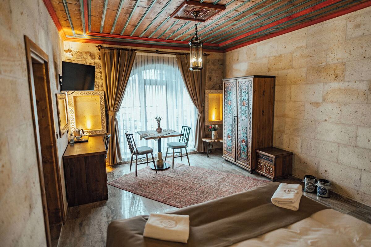A hotel room with a bed, a desk, a chair, a table, and a cabinet.