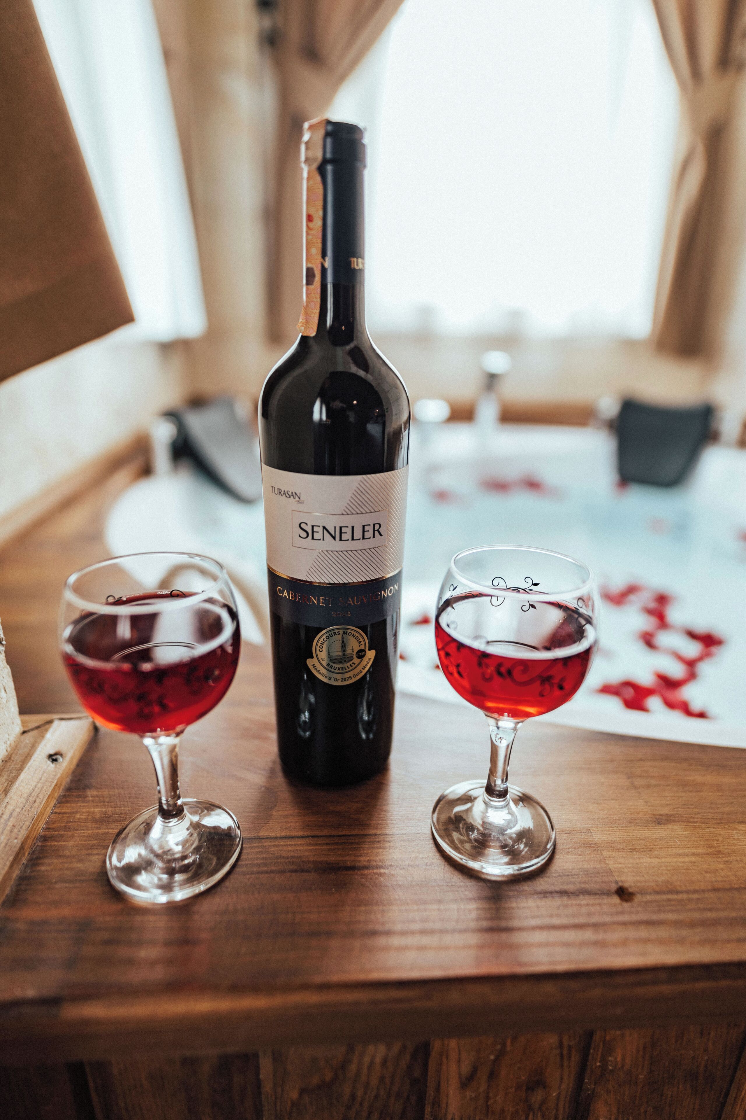 A bottle of wine and two glasses on a wooden table.