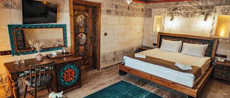 A bedroom with a bed, a desk, a chair, a TV, and a decorative mirror.