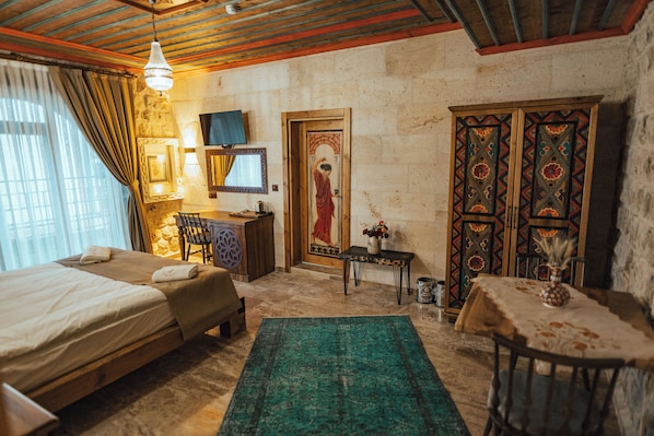A room with two beds, a desk, a chair, a table with a vase, and a decorative door. - Kallista Cappadocia (Nevsehir)