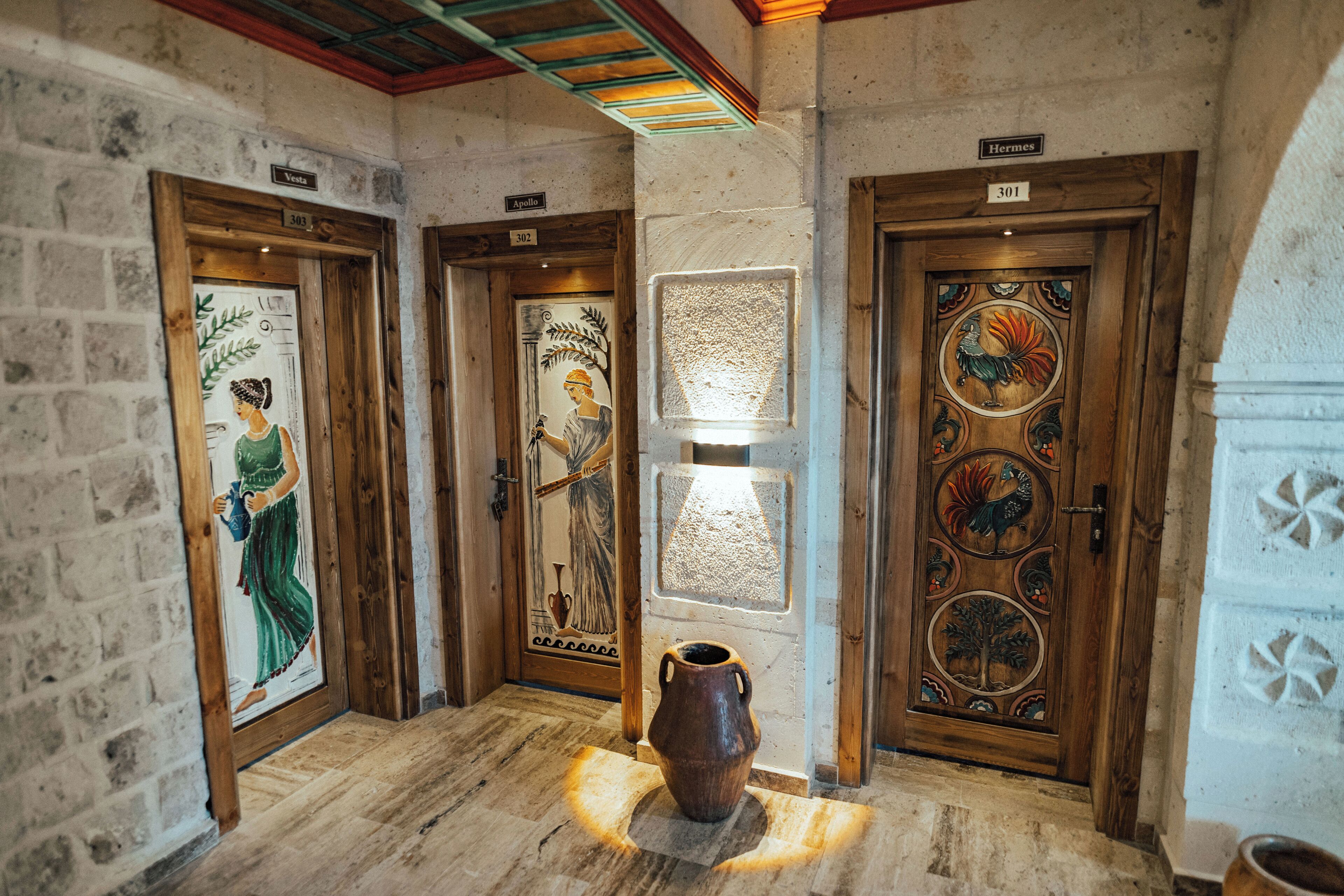 A hallway with three doors, each with a unique artwork and a sign above.