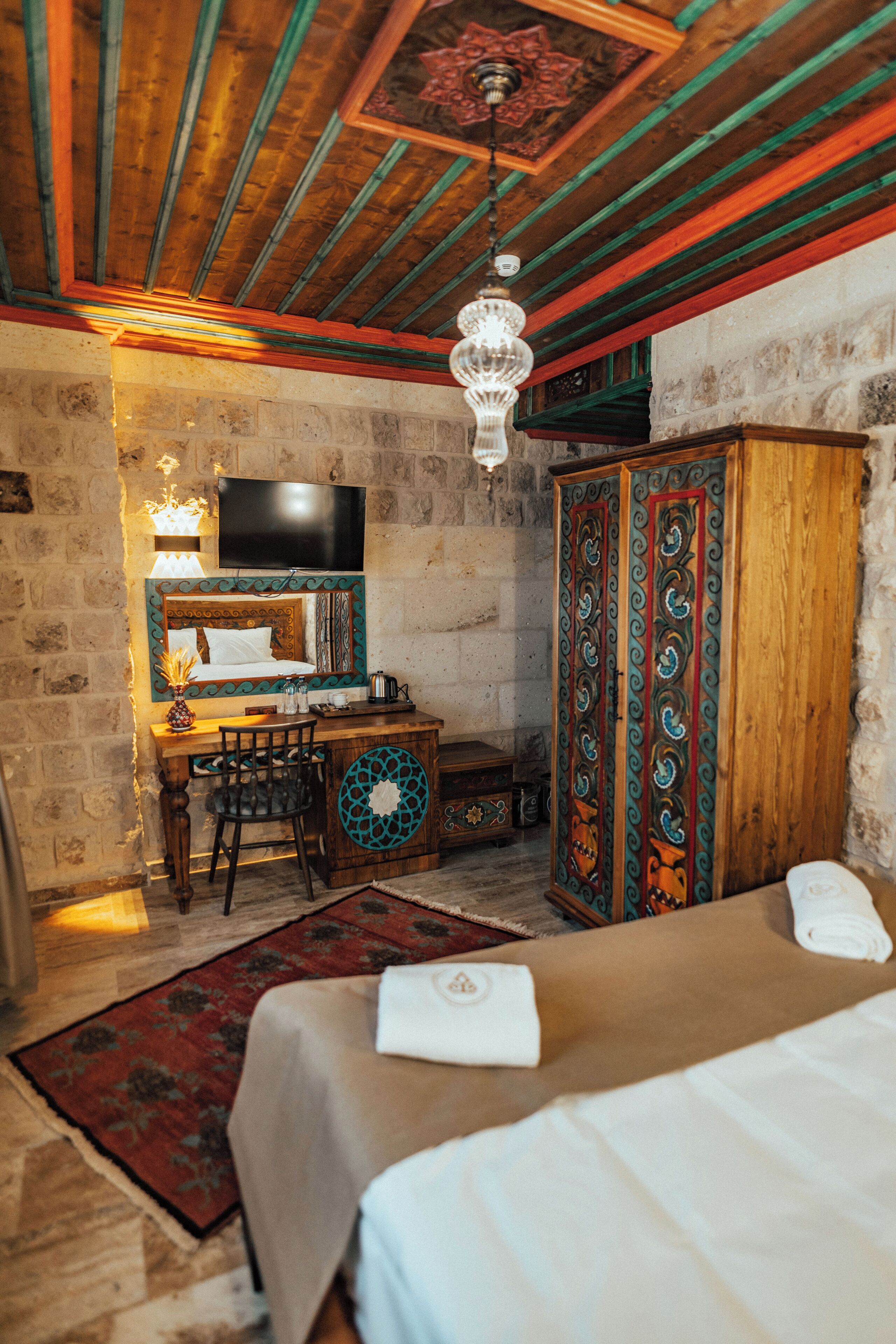 Una habitación con cama, un escritorio con silla, televisor y armario.