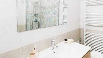Un bagno con un ampio specchio, un lavabo doppio e un portasciugamani.