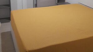 Makuuhuone, jossa on sänky, vaatekaappi, ovi ja riippuvalaisin.