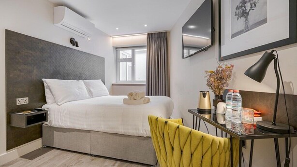 A modern hotel room with a bed, bedside table, desk, chair, and artwork on the walls. - Journeys Kings Cross - Hostel (London)