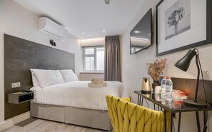 Ein modernes Hotelzimmer mit Bett, Nachttisch, Schreibtisch, Stuhl und Kunstwerken an den Wänden.