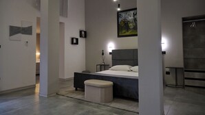 A modern bedroom with a large bed, bedside tables, a bench, and artwork on the walls. - Bellosguardo Suites (San Paolo Bel Sito)