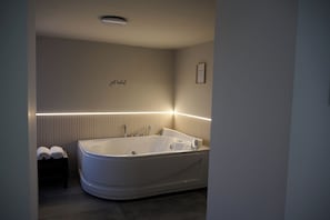 Une salle de bain moderne avec une baignoire sur pieds, un porte-serviettes et un certificat encadré accroché au mur.