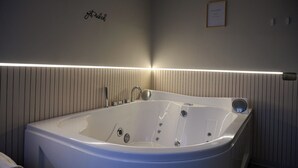 A modern bathroom with a large bathtub, a wall-mounted towel rack, and a framed sign on the wall. - Bellosguardo Suites (San Paolo Bel Sito)