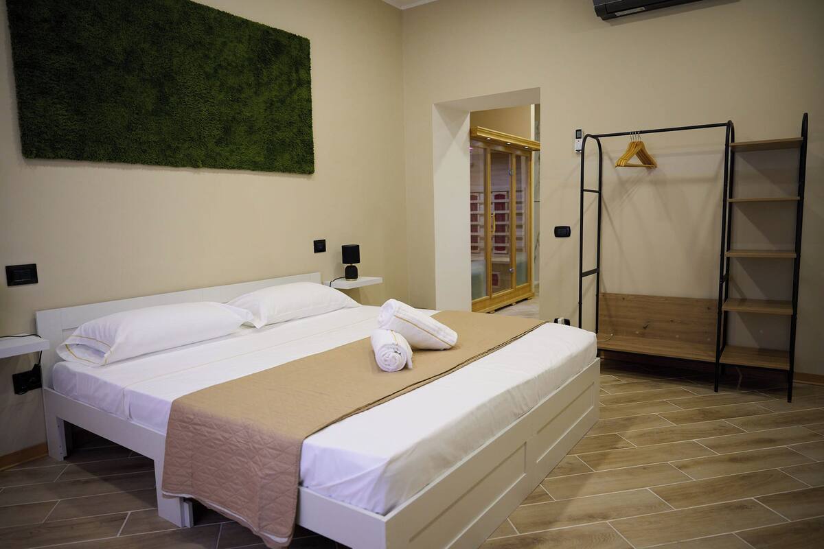 Una habitación de hotel con una cama, un estante de madera, un armario y un adorno verde en la pared.