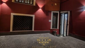 A hotel interior with a red wall, a tiled floor, and a logo at the bottom. - Bellosguardo Suites (San Paolo Bel Sito)